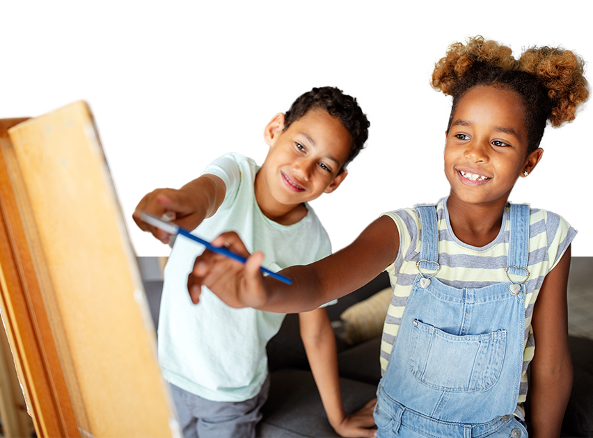 Niños sonrientes interactuando frente a un caballete, uno sostiene un pincel y señala, mientras el otro observa. El entorno es luminoso y acogedor, con colores cálidos.
